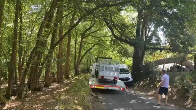 Two vehicles attempt to pass on a narrow rural lane