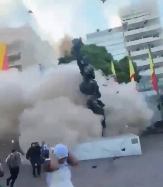 People are shown running as a large cloud of dust expands behind them.