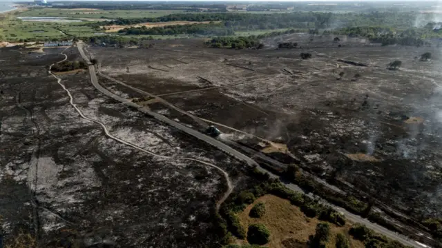 An aerial view of Dunwich Heath in Suffolk. Tracks and roads can be seen crossing through the charred, black landscape.One the edge of the black area are small patches of green,