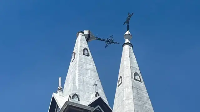 The top of a church spire with the very top of the spire has broken off an is lying horizontal