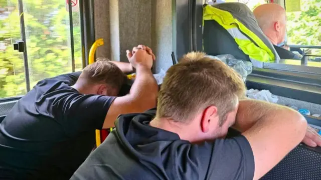 Two firefighters rest their heads on their arms in a fire appliance