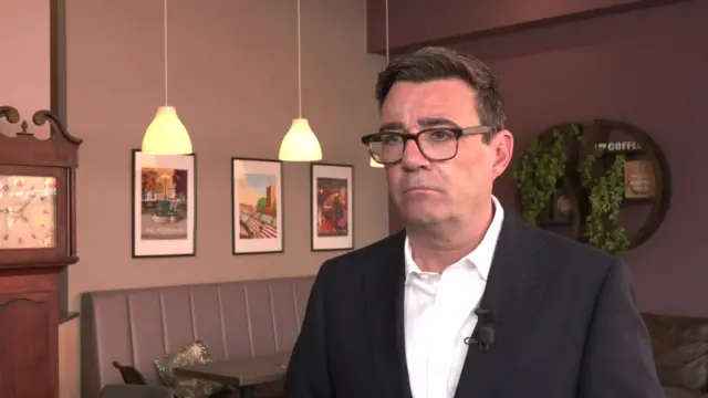 Burnham wears a white shirt and suit jacket