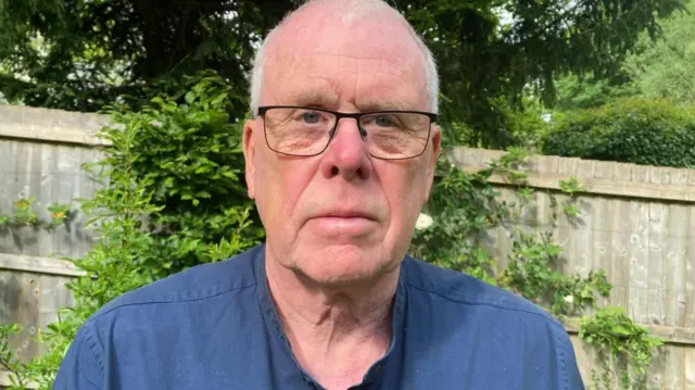 John Podmore is standing in front of a fence in a garden