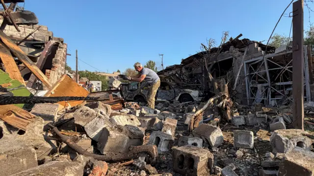 A man stands on top of a heap of rubble