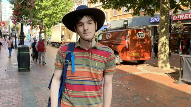 Bora Chaworth-Musters, wearing a stripey shirt and a black hat