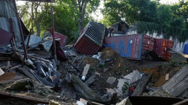 An employee removes debris at the compound of a City Children's Clinical Infectious Disease Hospital hit by an overnight missile strike, amid Russia's attack on Ukraine, in Kyiv, Ukraine August 11