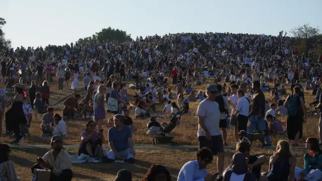 Hundreds of people pictured in Primrose Hill at dusk in London.