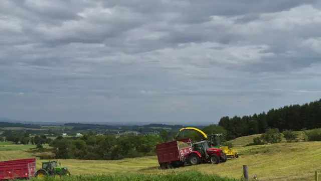 Clouds above a field being worked by two tractors in Kilmacolm, Inverclyde