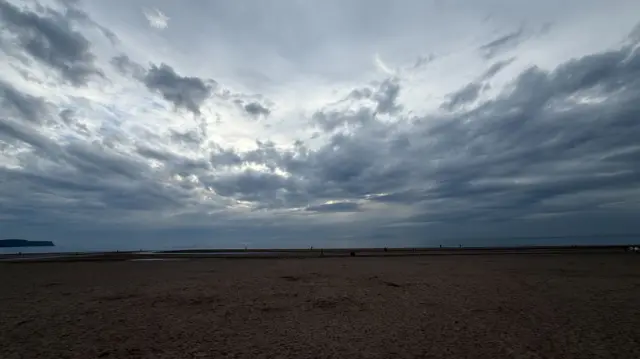 Thick clouds cast a gloomy sea on a beach in the UK.