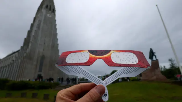 Raindrops collect on a pair of protective glasses ahead of a total solar eclipse, near the Hallgrimskirkja church and the statue of Norse explorer Leif Erikson in Reykjavik, Iceland