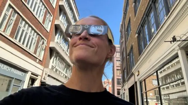 BBC journalist Katie Law wearing her eclipse glasses