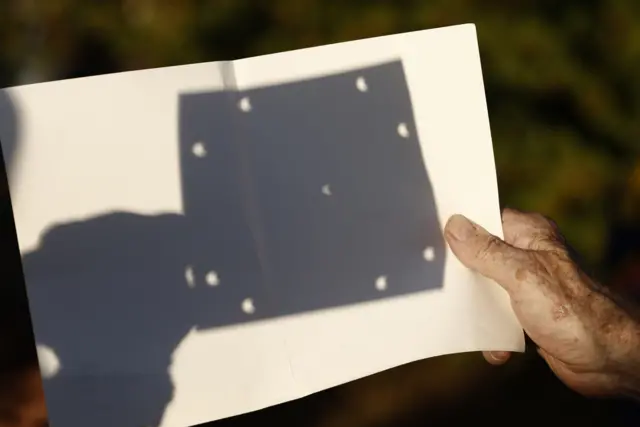 Shadow of eclipse on paper in park