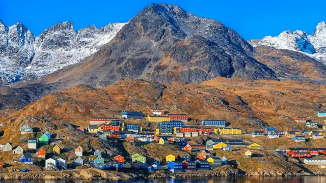Colourful houses on a mountain, with frosty mountains covered in snow behind