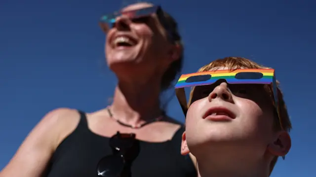 People shield their eyes with protective glasses during an eclipse event at Greenwich Observatory in London, Britain, 12 August 2026