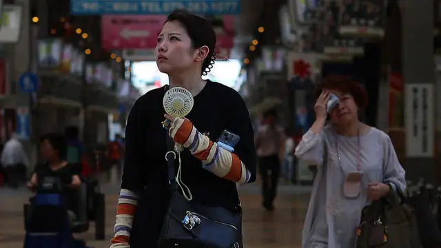 A woman holds a hand-held fan