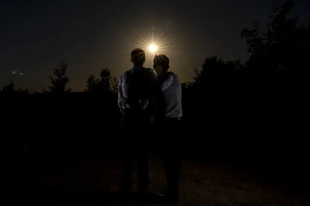 Two people hug as they watch the eclipse
