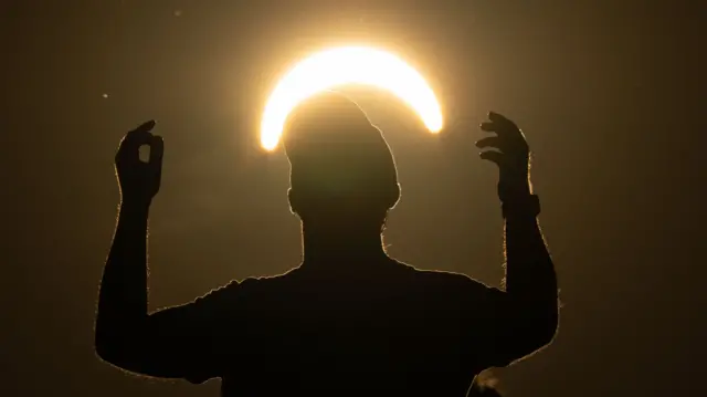 man dances during a partial solar eclipse on top of Great Feldberg mountain northwest of Frankfurt, Germany, 12 August 2026