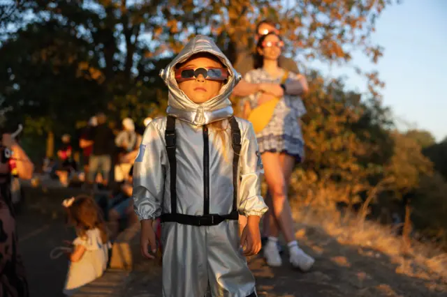 Spacesuit young girl with solar glasses in park