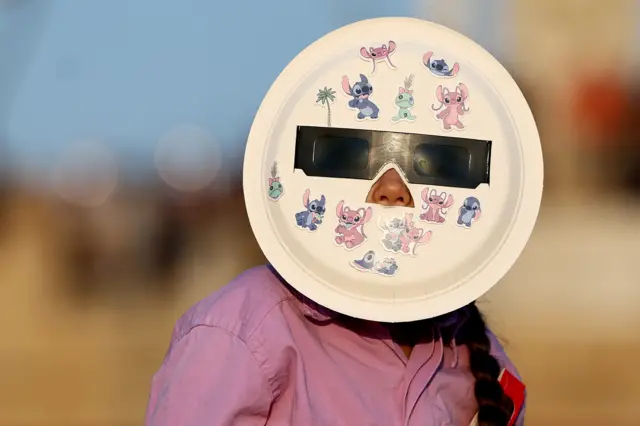 Girl with paper plate and solar glasses on face