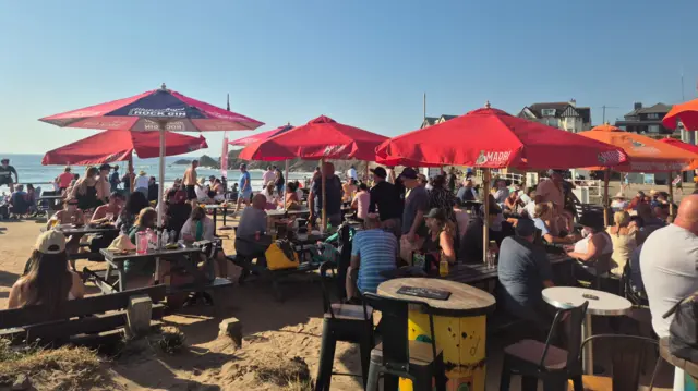 Busy tables on a beach under a sunny sky