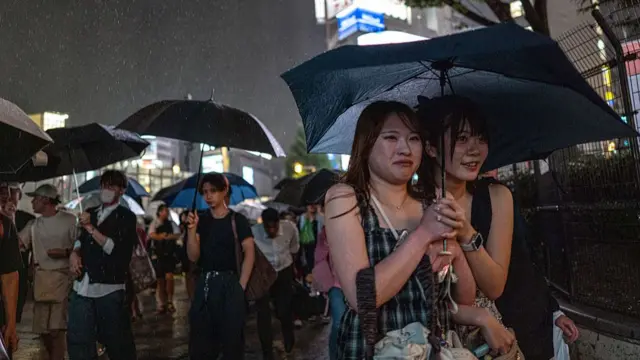 Two girls sharing an umbrella in the rain