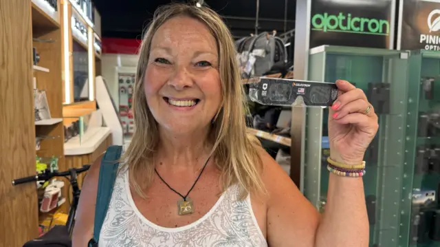 Jane holding her eclipse glasses up after purchasing them in Cardiff