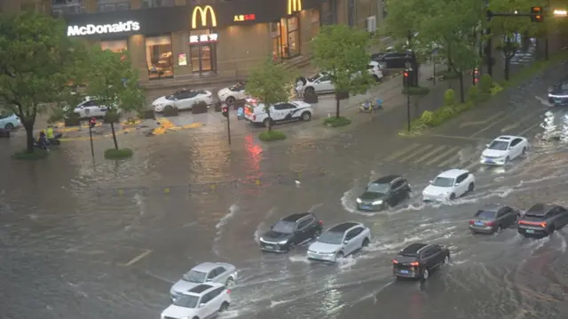 Cars attempt to navigate a flooded street in Taizhou, Zhejiang province