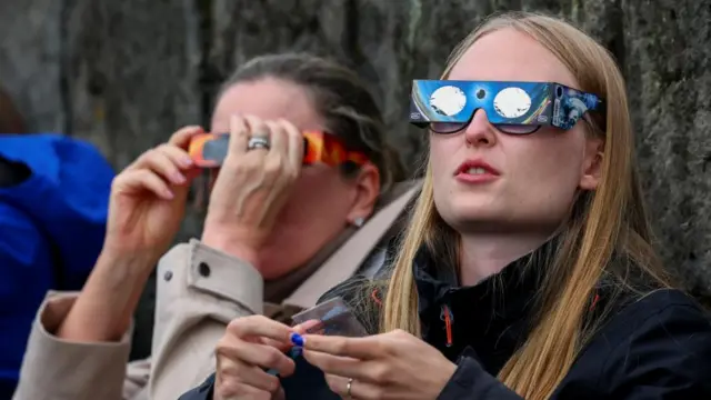 Two women watch the eclipse in Reykjavik, Iceland, before it reaches totality.
