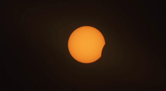 An orange orb with a chunk out of it against a dark background