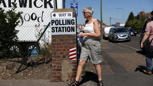 A woman walking past a polling station sign on the day of the Clacton by-election