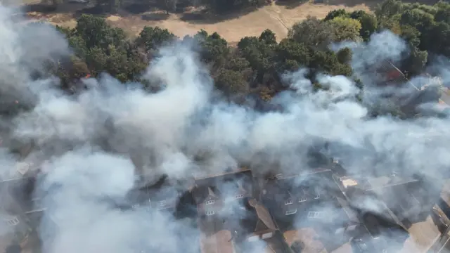 Smoke rising from above homes next to a golf course