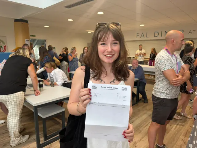 Ella Thomas smiles as she holds up her results