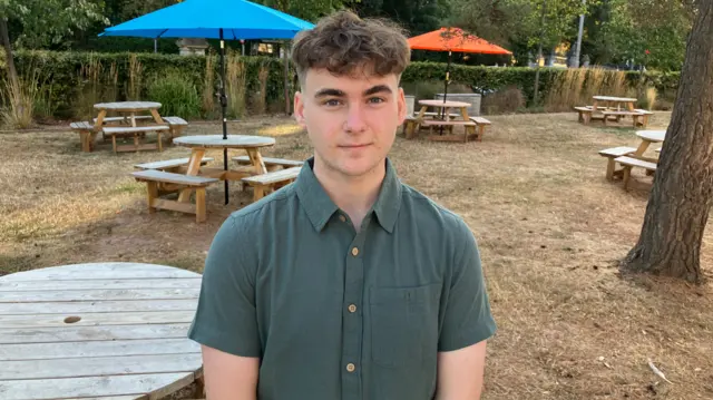 A young man with brown curly hair and a shirt on
