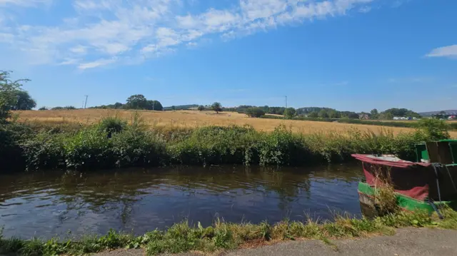 A canal boat on a river with only a few clouds in the sky