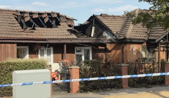 A roof has partially collapsed on a bungalow. The inside of the property is exposed and police tape cuts the scene off to the public.