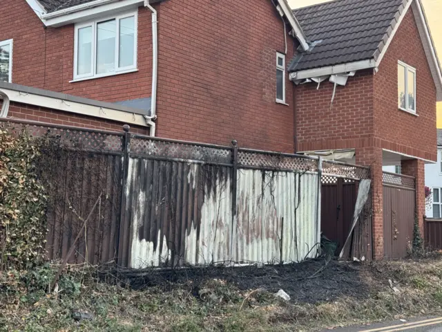 A fire-damaged fence on a residential property.