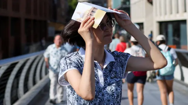 A woman covers her head with a leaflet