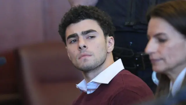 Luigi Mangione in courtroom with his eyebrows raised and a serious expression on his face