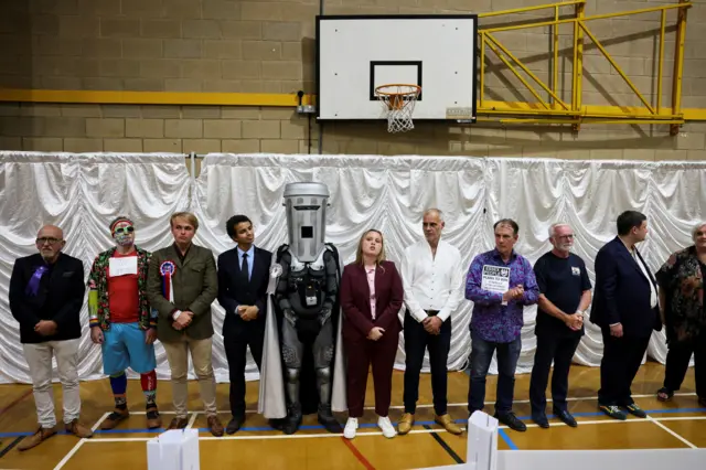 A line of candidates stand in a leisure centre