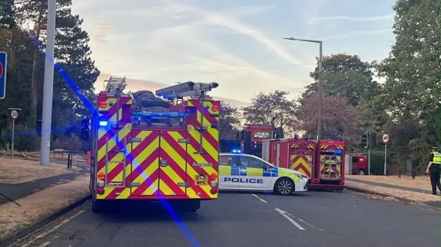 Fire engines and a police car block a main road in Stourbridge. A police officer can be seen walking on the pavement on the right.