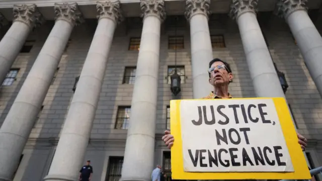 A man holds a placard outside court which reads: "Justice not vengeance"