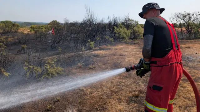 Firefighters use hoses on gorse fire