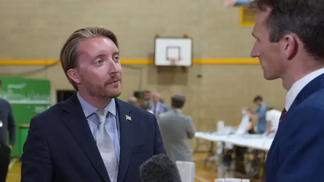 Reform UK councillor Jaymey McIvor talks to the media as votes are counted for the Clacton by-election at Clacton Leisure Centre in Essex. The by-election was triggered by local MP and Reform UK leader Nigel Farage quitting in protest at the scrutiny of his finances from the press and the parliamentary authorities. Picture date: Friday August 14, 2026