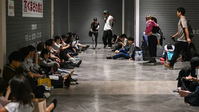 Stranded passengers rest on the floor at the shopping mall at Chiba Metro Station in Chiba