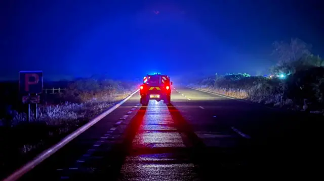 A fire service vehicle on a deserted road at night.