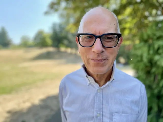 A man with short grey hair and glasses.