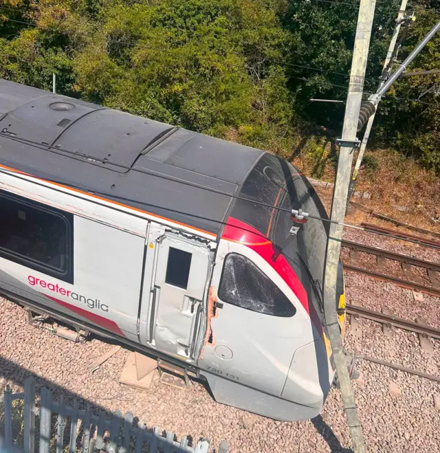 An image of a derailed train that has come off the tracks next to a fence in Essex - image taken at a side angle.
