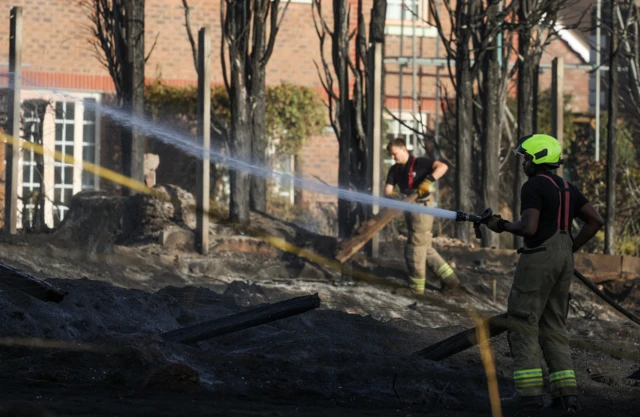 A firefighter works to damp down a fire