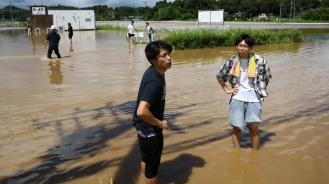 Two men wade through flood water