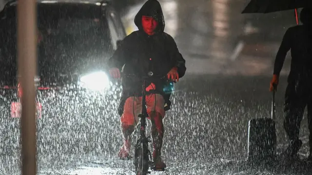 A man rides his bike along a flooded road near Chiba metro station in Chiba